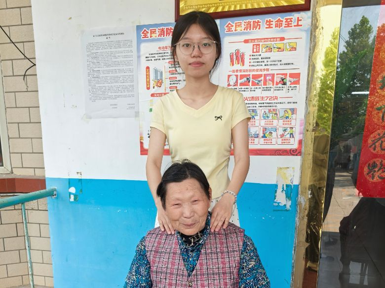 圖為實踐團成員劉飛彤在老年公寓為老人捏肩膀